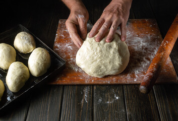 Male hands prepare dough for buns on the table close-up. Baker baking pies at home