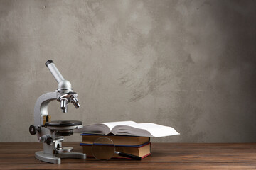 Back to school - books and microscope on the wooden desk in the auditorium, Education concept