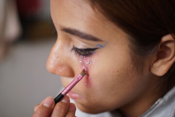 Teenage latin hispanic girl putting on makeup