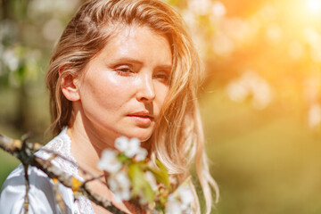 Blond garden. Portrait of a blonde in the park. Happy woman with long blond hair in a blue dress.