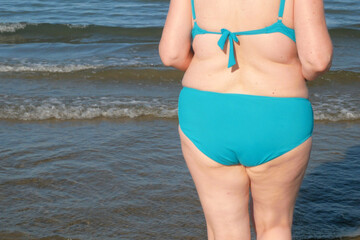Fototapeta premium Plus size senior woman in swimsuit dancing on the sea beach in sunny day. Happy people in vacation concept. International Women's Day.