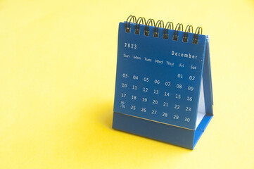 December 2023 blue desk calendar on yellow cover background with customizable space for text. Copy...