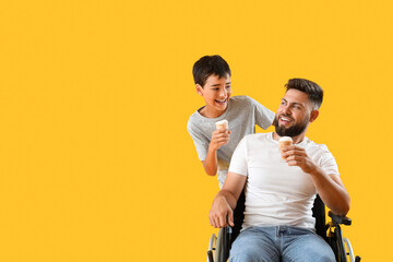 Little boy and his father in wheelchair with ice creams on yellow background