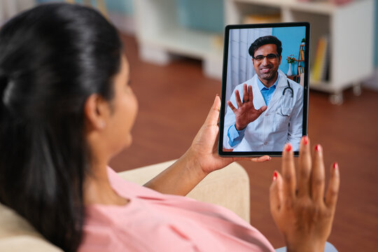 Shoulder Shot Of Indian Pregnant Woman Consulting Doctor On Video Call At Home - Concept Telemedicine, Virtual Healthcare And Remote Consultation.