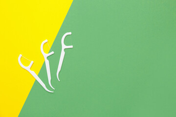 Floss toothpicks on yellow and green background