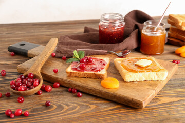 Wooden board of tasty toasts with jam on table