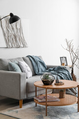 Interior of cozy living room with grey sofa and coffee table near white wall