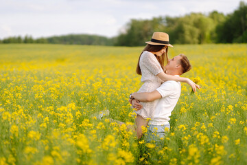 Fototapeta premium Young Couple in the blooming field. Nature, vacation, love, relax and lifestyle. Summer landscape. 