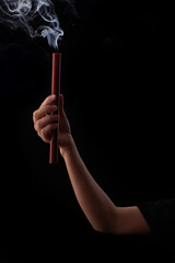 Fototapeta premium Hand holding extinguished red wax candle with beautiful smoke