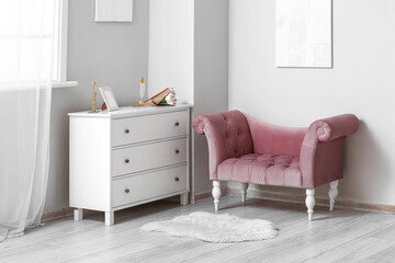 Interior of light room with pink armchair and commode