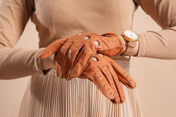 Stylish young woman in leather gloves on beige background, closeup