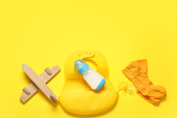 Bottle of milk for baby and  accessories on yellow background