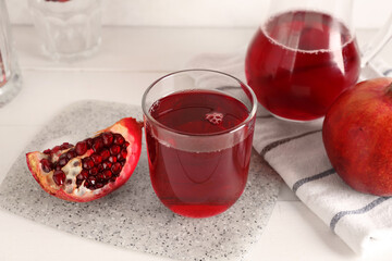 Jug and glass of fresh pomegranate juice on white wooden table