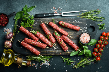 Raw Lyulya kebab with spices and herbs, ready for cooking. On a dark stone background. Top view....