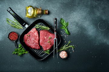 A piece of veal meat with spices in a pan, on a stone background. Veal, meat. Top view.
