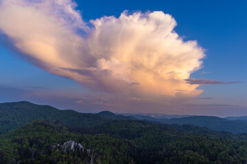 Fototapeta na wymiar Large clouds at dusk above the forested mountains, Bijele stijene reserve in Croatia