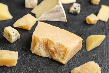 Pieces of tasty cheese on dark background