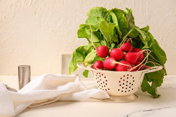 Colander with fresh radish on table