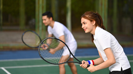 Two tennis players crouching in ready position and holding racket while waiting for serving ball during a competitive match