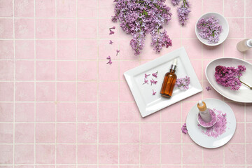 Fototapeta na wymiar Composition with bottles of lilac essential oil, sea salt and flowers on pink background