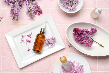 Fototapeta na wymiar Composition with bottles of lilac essential oil, sea salt and flowers on pink background