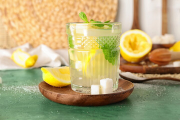 Glass with fresh lemonade on green table