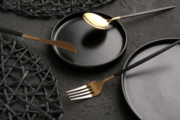 Plate with golden cutlery on black background