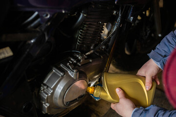 Fototapeta na wymiar man pouring new engine oil into a motorcycle