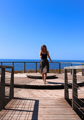 A female traveler running gracefully towards camera. Front view of a girl running with the horizon and the ocean in the background.