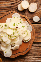Board with slices of fresh daikon radish on wooden background