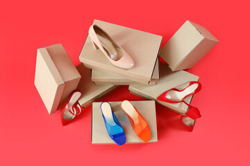 Cardboard boxes with different stylish high-heeled shoes on red background