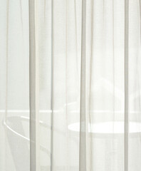 A white clean curtain covers the window in the bedroom see-through the outside.