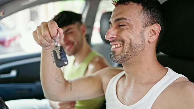 Two men couple smiling confident holding keys at street