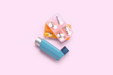 Asthma inhaler and boxes with pills on pink background