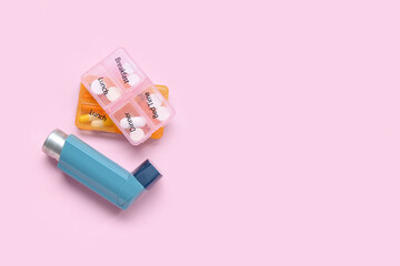 Asthma inhaler and boxes with pills on pink background