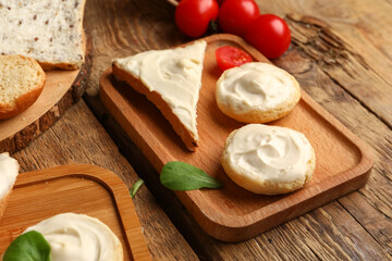 Board of tasty croutons and toast with cream cheese on wooden background