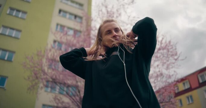 Portrait of a free-spirited girl pulling down her hood in an urban neighborhood