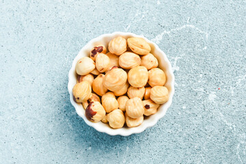 Closeup view of hazelnuts in a white bowl on a light stone background. Healthy snacks. Nuts