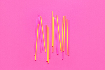 Different plastic straws on pink background