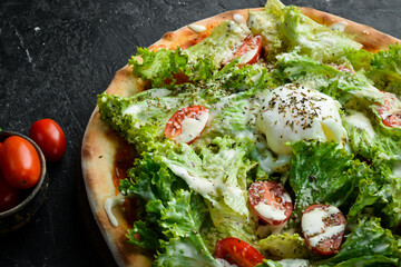 Homemade Caesar pizza. Takeaway food. Home delivery of food. On a black stone background.