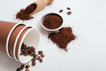 Cups with coffee beans and powder on light background