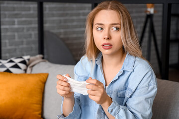 Allergic young woman with tissue at home