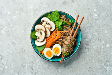 Buckwheat soba pasta with egg, mushrooms and microgreens. On a gray stone background. Side view....