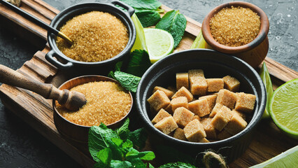 Brown cane sugar cubes in a bowl. On a black stone background. In a black bowl.