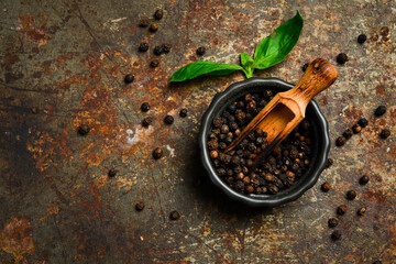 Fragrant black peppercorns in a bowl. Spices and condiments. Top view. On a dark textured background.