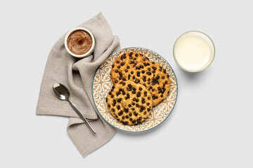 Plate with cookies, glass of milk and towel on light background
