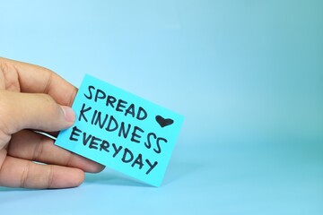 Spread kindness everyday reminder concept. Hand holding a bright green paper message note.