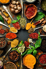 Colored spices in spoons and bowls. Aromatic spices for cooking. On the background of black stone....