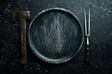 Grill fork and Wooden plate. Table setting. Top view. On a stone dark background.