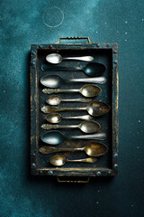 A set of vintage spoons in a wooden box. Old cutlery. Top view. On a dark stone background.